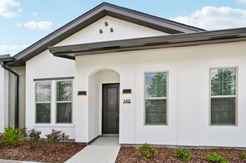 A white house with a black door and windows at The Hadley - North Port, FL Apartments, North Port, FL